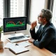 A small business owner analyzing financial trading charts and business reports for a diversification strategy.