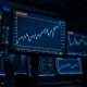 Financial trading desk monitor showing AUD/USD forex chart rebounding higher.