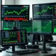 Financial trading desk with monitors showing stock market data and ETF ticker symbols.