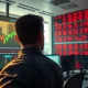 Trader monitors surging US dollar index and falling gold prices on screen during stock market decline.