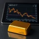 Gold bullion bar with financial chart illustrating price pressure below $5,200.