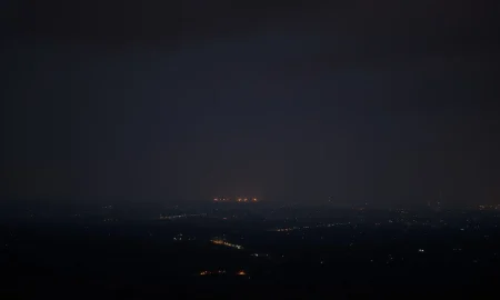 A distant view of a city skyline at night under a tense, cloudy sky, representing the region of reported strikes.