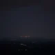 A distant view of a city skyline at night under a tense, cloudy sky, representing the region of reported strikes.