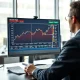 Trader analyzes lean hog futures chart and USDA price data on a professional commodities trading desk.