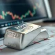 Silver bullion bar on a financial chart as prices hold below $80 per ounce.