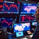 Trader analyzes falling stock market charts amid Middle East conflict news, representing the March 2026 market retreat.
