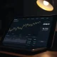 A tablet showing a Bitcoin chart and the American Bitcoin fund's holdings of 7,000 BTC.