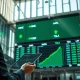 Financial analyst monitors trading board showing USMC ETF and major tech stock tickers surging.