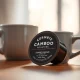 A close-up of a Cambio Roasters compostable coffee pod next to a full mug of coffee.