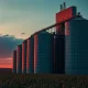 A grain elevator and corn field at dusk, representing the agricultural commodity market.