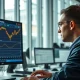 A trader monitors gold price charts on a financial terminal as markets react to geopolitical news.