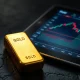 Gold bullion bar next to a financial chart showing price decline.
