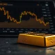 Gold bullion bar with a financial chart showing a price decline in the background.