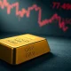 Gold bullion bar with financial charts in the background, representing the drop in gold prices.