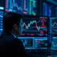 A trader monitors NZD/USD currency pair charts on a financial trading desk.
