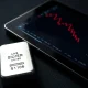 A silver bullion bar next to a tablet showing a declining price chart.