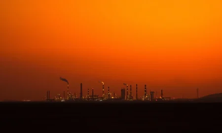 An oil refinery at dusk as WTI crude prices hold near $89 amid Middle East tensions.