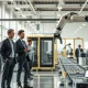 Workers alongside a robotic arm in a modern US factory, illustrating AI and automation in the labor market.