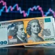 Australian Dollar and US Dollar banknotes on desk with financial chart showing decline