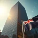 Sydney financial district skyline at dawn with Australian flag in foreground, representing pre-budget forex market caution.