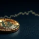 Bitcoin coin on dark surface with glowing $60,000 support line chart in background