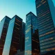Modern city skyline at dusk with digital data streams and blockchain network patterns on buildings