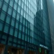 Exterior of a modern glass office building, representing the headquarters of a financial firm under federal investigation.