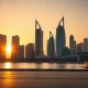 Abu Dhabi skyline at sunset with modern financial district buildings reflecting in calm water