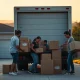 Family packing moving truck in front of California home with capitol building in background
