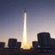 Futuristic missile defense system with interceptor launching at dusk in desert landscape.