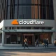 Cloudflare headquarters in San Francisco on a clear morning, with employees entering and exiting the building.