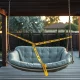Empty hanging patio swing with caution tape in a backyard, illustrating a product safety recall.