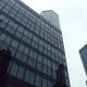 Exterior of a modern glass office building in London's financial district under overcast skies.