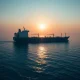 Large oil tanker anchored in the Strait of Hormuz under hazy golden sunset light
