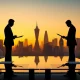 Two business silhouettes facing each other over a conference table with London skyline in background