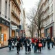 Shoppers on a retail street in a Eurozone city with storefronts and subdued foot traffic