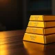 Stack of gold bullion bars on a dark surface with soft lighting