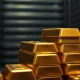 Close-up of stacked gold bars in a vault with one bar separated, representing market pullback and potential breakout.