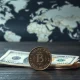 Mexican Peso coins and US dollars on a table with a world map in the background, representing currency market volatility.