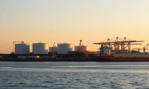 Aerial view of a US Gulf Coast LNG export terminal at sunrise with storage tanks and loading dock
