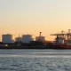 Aerial view of a US Gulf Coast LNG export terminal at sunrise with storage tanks and loading dock