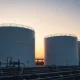 Natural gas storage facility at sunset with large white tanks and industrial piping