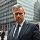 Serious businessman in suit outside Manhattan skyscraper, representing NYC real estate interests.