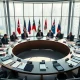 International delegates seated at a round table in a modern conference room discussing AI governance.