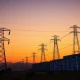 Data center complex in Northern Virginia with electrical transmission towers at sunset, illustrating grid strain from AI demand.