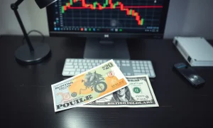 British Pound and US Dollar banknotes on a desk with a trading chart in the background.