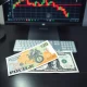 British Pound and US Dollar banknotes on a desk with a trading chart in the background.