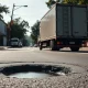 Commercial truck with mounted camera driving past a pothole on a city street