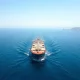 Oil tanker sailing through the Strait of Hormuz with coastline in background under bright daylight.