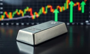 Silver bullion bar on dark wood with financial charts in background
